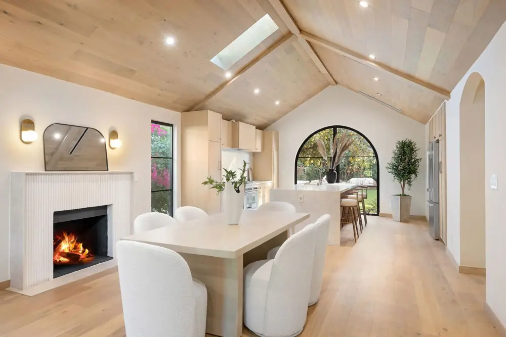 Modern dining room with arched window vaulted wood ceiling skylights and elegant wall sconces