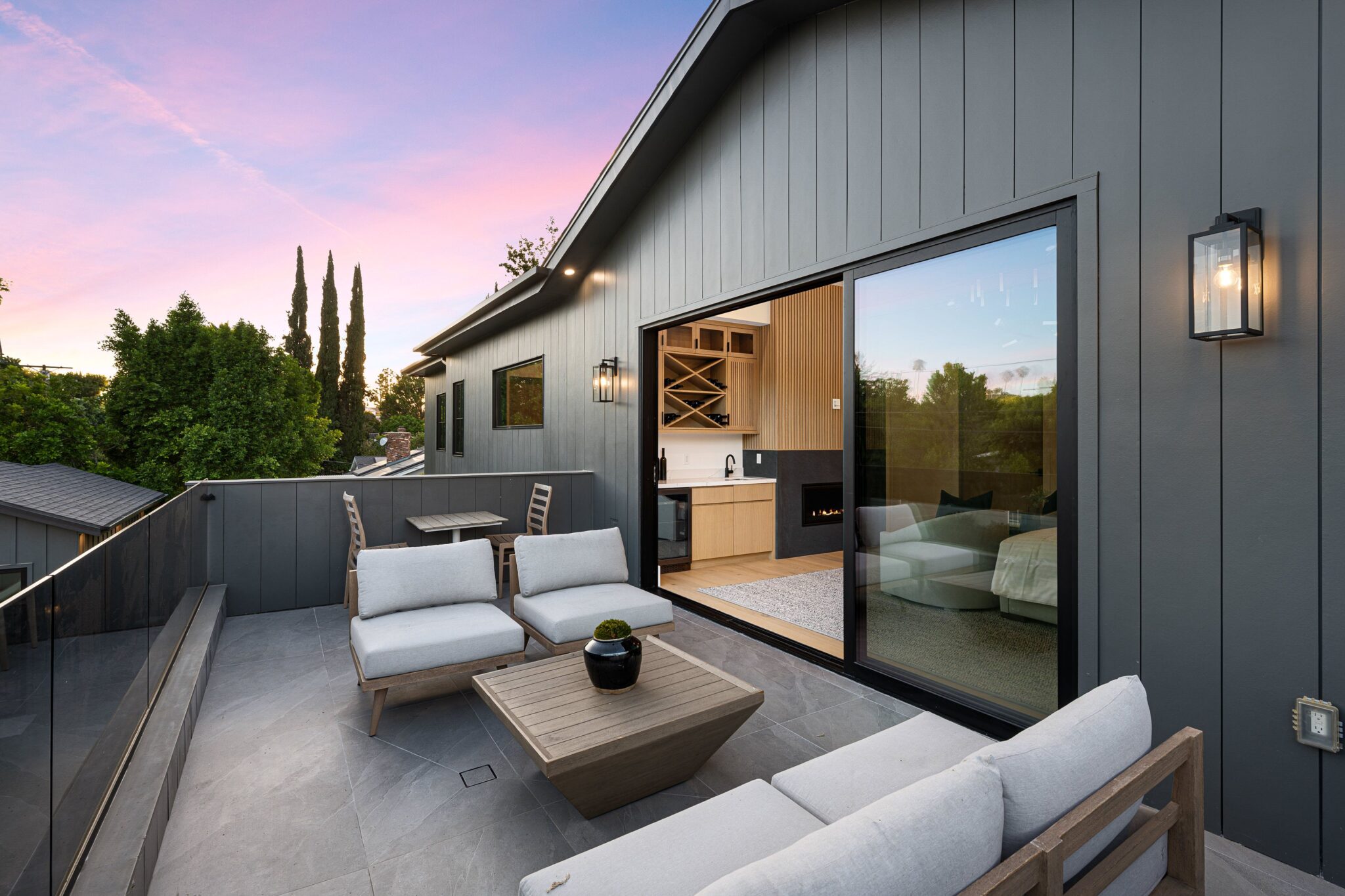 Your Guide to Beautiful Remodel Services by JJ. Builders 3 Modern outdoor patio with comfortable seating and a view of the sunset sky, adjacent to a stylish interior living space.